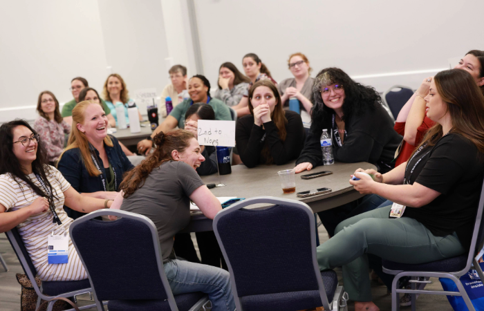 Attendees around a table smiling and laughing