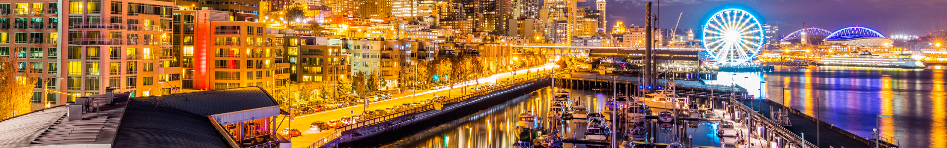 L2-Header Night shot of seattle harbor with ferris wheel and bridges in background.